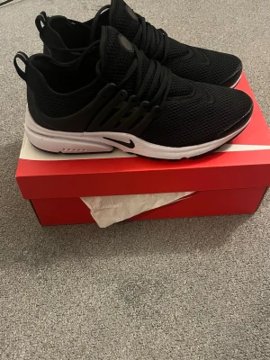 Svarta Nike Presto sneakers - Säljer ett par svarta Nike Presto sneakers med mesh-överdel och vita sulor. Skorna har snörning, rund tå och en sportig vibe. Perfekta för dig som gillar stilrena och bekväma sneakers. Kommer i originalkartong. Jätte fin skick hör av er vid frågor