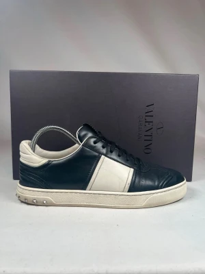 Valentino Garavani Flycrew sneakers - (Nypris 6440kr)Snygga Valentino Garavani Flycrew sneakers i svart och vitt skinn. Klassisk låg modell med svarta snören, rund tå och coola nitar på hälen. Tjock vit sula och diskret logga på plösen. Perfekta för dig som vill ha en lyxig touch till din outfit. 