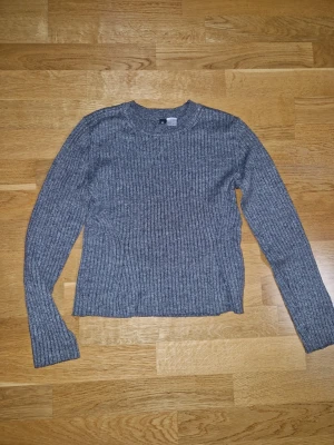 Grå ribbad stickad tröja CUBUS - Säljer en grå ribbad stickad tröja från Cubus i storlek S. Tröjan har lång ärm, rund halsringning och är i mjukt material som passar perfekt till kyligare dagar. Enkel och stilren design som är lätt att matcha.