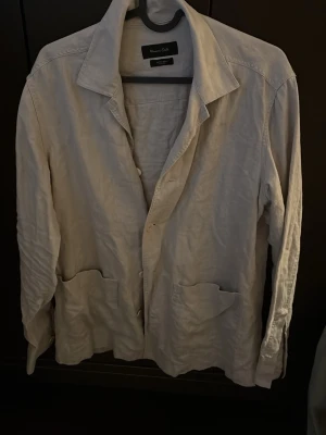Beige linnéovershirt från Massimo Dutti - Säljer en stilren beige overshirt från Massimo Dutti i 100% linne. Jackan har klassisk krage, knäppning framtill och två stora fickor. Perfekt för lager på lager och ger en chill men ändå uppklädd vibe. Rätt säker på att det är strl S, sitter som S/M