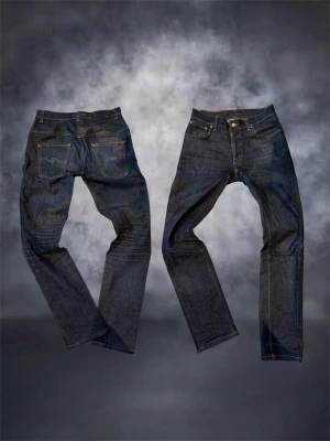 Nudie jeans  - Säljer ett par mörkblå Nudie Jeans Thin Finn i modellen Dry Indigo Dips. Jeansen är tillverkade av 99% ekologisk bomull och 1% elastan för lite stretch. Klassisk femficksmodell med orange sömmar och rak passform. Perfekta för dig som gillar stilrena jeans.