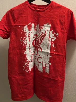 Röd Liverpool FC t-shirt - Snygg röd t-shirt med Liverpool FC-logga och coolt vitt tryck framtill. 