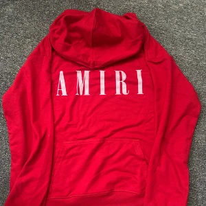 Röd hoodie från Amiri - En röd hoodie från Amiri med stort vitt logotryck på bröstet.