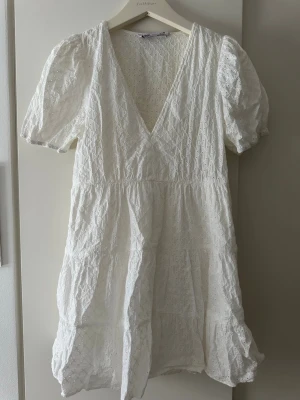 Vit kort klänning med broderi från Zara - Supersöt vit kort klänning från Zara med puffärmar och v-ringning. 