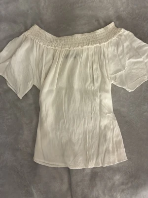 vit offshoulder topp  - Säljer en superfin vit offshoulder topp från BikBok i storlek M. Toppen har smockad kant upptill och vida, korta ärmar. Materialet är lätt och luftigt, perfekt för varma dagar. Enkel att styla med både jeans och kjol.