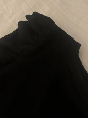 Svart topp med volangärmar från Zara - Säljer en svart topp från Zara i storlek M. Toppen har korta volangärmar som ger en snygg och trendig look. Materialet känns mjukt och stretchigt, perfekt till många olika outfits. Enkel rund halsringning och rak passform.