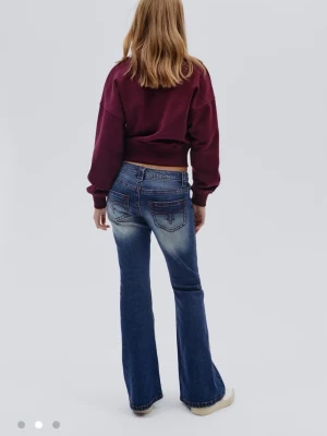 Blå bootcut jeans med broderade fickor - Snygga blå bootcut jeans med markerad tvätt och broderade bakfickor i rött. Jeansen har låg midja och klassisk femficksdesign. 