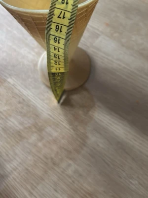 Strutformad glasskopp i plast - Säljer 3 stycken beige strutformad glasskopp i plast med rutmönster som liknar en glasstrut. Koppen har fot och mäter cirka 17 cm på höjden och 10 cm i diameter upptill. Perfekt för att servera glass eller dessert på ett kul sätt. Har aldrig använt dem