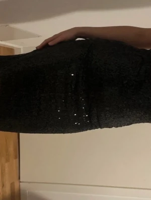 Svart glittrig långklänning - Snygg svart långklänning med tunna axelband och glittriga paljetter över hela klänningen. 