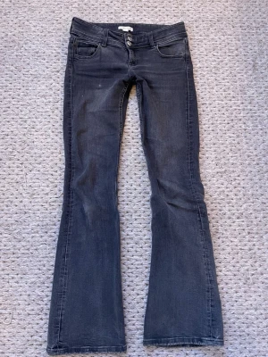 Mörkgrå bootcut jeans  - Mörkgrå bootcut jeans från Gina Tricot med två knappar i midjan och klassiska fem fickor. 