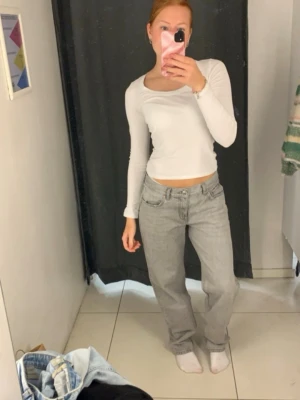 Vit ribbad långärmad topp Monki - Säljer en vit långärmad topp från Monki med rundad urringning. Toppen är ribbad och har en slim passform som sitter snyggt på kroppen. Perfekt att styla med jeans eller kjol för en clean look.