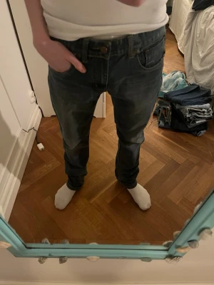 Mörkblå raka jeans - Säljer ett par mörkblå jeans med rak passform och klassiska fem fickor. Jeansen har en något tvättad look och är tillverkade i denim. Perfekta för en avslappnad stil.