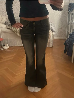 Bootcut jeans i mörkgrå denim - Strl 27/32 Snygga bootcut jeans i mörkgrå tvätt med låg midja och klassisk femficksdesign. Jeansen har en lätt utsvängd passform nertill och detaljer med dragkedja och knapp framtill. Perfekta för dig som gillar en retroinspirerad look. Obs lånade bilder ifrån hon jag köpte av. Säljer pga att de var lite för små i midjan