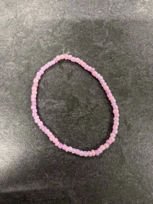 Rosa pärlarmband Storlek M  - Ett enkelt armband med små, glansiga rosa pärlor trädda på elastisk tråd. 