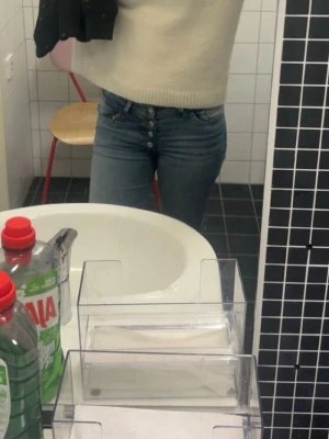 Blå jeans med knäppning framtill - Säljer ett par klassiska blå jeans med hög midja och synlig knappgylf. Jeansen har raka ben och tydliga kontrastsömmar. Materialet är denim i bomull. Perfekta för en avslappnad och trendig look.