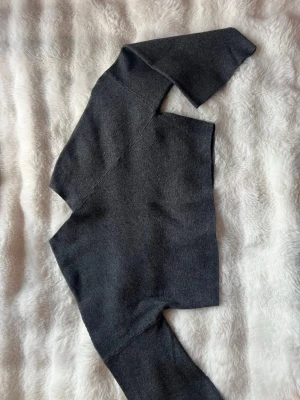 Grå stickad tröja från Weekday - Mjuk och stilren grå stickad tröja från Weekday med lång ärm och enkel design. Perfekt för lager på lager och passar till det mesta. Tröjan har mer unik v formad halsringning och är tillverkad i ett tunt, stretchigt material. Storlek S/XS