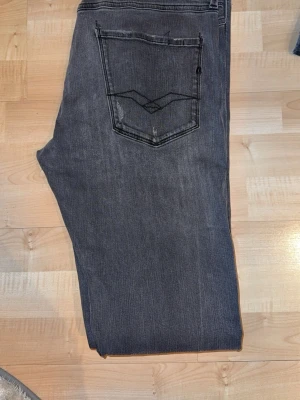 Grå jeans med bakficka och brodyr - Säljer ett par grå jeans med klassisk femficksdesign och snygg brodyr på bakfickan. Jeansen har rak passform och är tillverkade i ett mjukt denimtyg. Perfekta för en avslappnad och stilren look. W33 L33 