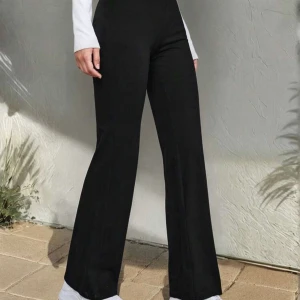 Högmidjade Leggins - Säljer ett par svarta bootcut byxor med hög midja. De har en snygg, figurnära passform upptill och vida ben nedtill. Materialet är mjukt och stretchigt, vilket gör dem riktigt sköna att ha på sig. Perfekta för dig som gillar en stilren look med lite edge.