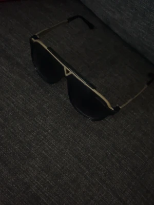 Solglasögon - Bilderna visar ett par svarta solglasögon med guldfärgade detaljer, mycket bra skick mer bilder dm 