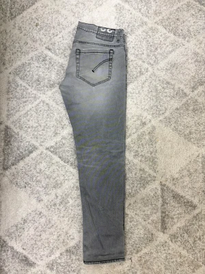 Grå Dondup Jeans George - Säljer ett par grå jeans från Dondupmed skinny fit..  färgen är ljusgrå med lätt tvättad look. Perfekt för dig som gillar smalare passform och stilren design. Storlek 33 men Passar mig som har 32. Pris kan diskuteras vid snabb affär, fraktar samma dag som beställning!
