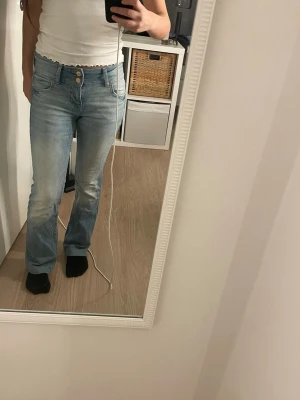 Ljusblå bootcut jeans från Bershka - Säljer ett par ljusblå jeans från Bershka i storlek 34. Jeansen har bootcut-modell, klassisk femficksdesign och dubbla knappar i midjan. Tillverkade i jeansmaterial med en snygg tvättad look och lätt utsvängda ben.