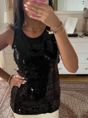 Svart paljettlinne - Linne med glittriga paljetter, perfekt till nyår! Passar XS!