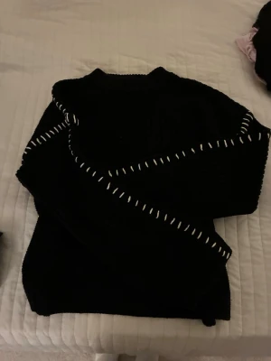 Svart stickad tröja från Gina Tricot - En super snygg Svart stickad tröja från Gina Tricot i storlek S. Tröjan har lång ärm och coola vita sömmar längs axlar och ärmar som är unika.. Perfekt för dig som gillar unika detaljer.