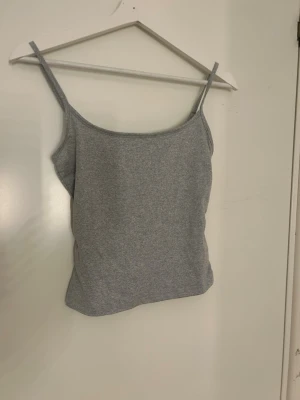 Grå linnetopp från SHEIN XS - Säljer en enkel och stilren grå linnetopp från SHEIN i storlek XS. Toppen har smala axelband och är tillverkad i mjuk polyester med lite stretch. Perfekt för sommaren och enkel att matcha med jeans eller shorts.