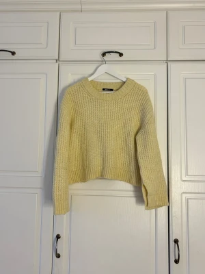 Ljusgul stickad tröja Gina Tricot💖 - Supermysig ljusgul stickad tröja från Gina Tricot i storlek S. Tröjan har en grovstickad struktur, ribbad rund hals och ribbade muddar vid ärmslut och nederkant. Modellen är lite croppad och har lång ärm, perfekt för att ge en chill vibe.