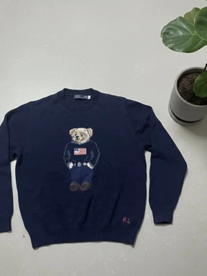 Ralph Lauren Teddy Bear Stickad Tröja (M) - 🧸 Ralph Lauren Teddy Bear Stickad Tröja – Mörkblå 💙 Färg: Mörkblå, stilren och exklusiv 📏 Storlek: L (passar som M) ✨ Skick: Mycket bra, sparsamt använd 🐻 Ikonisk teddy bear-design framtill 🧵 Mjuk, varm och bekväm stickning 🌟 En av Ralph Laurens mest klassiska modeller 🛍️ Perfekt för höst, vinter och layering 🔥 Passar både casual och smart-casual 🎁 Grym presentidé 📸 Se bilder för skick och detaljer