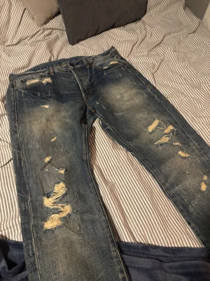 Ralph Lauren Jeans - Säljer ett par blåa slim fit jeans från Ralph Lauren med feta slitningar och distressed detaljer på både fram och baksida. Jeansen säljs pga fel storlek, använt 1 gång i min ägodom. Skick 9/10. Bara att höra av sig vid frågor!