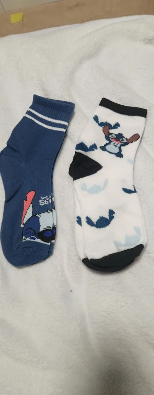 Stitch strumpa i blått och vitt - Supersnygg väst med Stitch-motiv i olika blå nyanser och vitt. Västen har en klassisk form med ribbad kant och tryckt Stitch-figur framtill. Materialet är mjuk bomull med inslag av polyester för extra komfort. Perfekt för dig som älskar tecknade karaktärer och vill sticka ut med en unik look. En st.för 20kr två för 30kr.