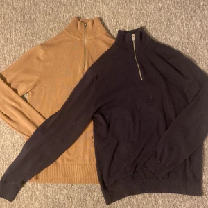 Selected Homme half zip stickad tröja - Två stilrena stickade tröjor från Selected Homme i storlek M. Ena är mörkblå och den andra är beige/brun båda med ribbad krage och half zip-dragkedja framtill. Perfekt för lager-på-lager och snyggt till jeans eller chinos. Två för 500 eller 1 för 300. Skriv vid minsta fundering 