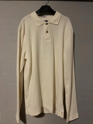 Vit pikétröja från H&M slim fit - Säljer en vit långärmad pikétröja från H&M i slim fit-modell. Tröjan har en klassisk krage, två knappar framtill och är tillverkad i ett strukturerat bomullstyg med diskret rutmönster. Perfekt för dig som gillar stilrena och enkla plagg. Perfekt för varmare dagar! Hör av er vid intresse🤩