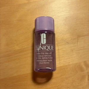 Clinique Take The Day Off makeup remover - Clinique Take The Day Off makeup remover i en liten genomskinlig plastflaska med lila skruvlock. Produkten är parfymfri och testad för allergier, och används för att ta bort smink från ögonlock, fransar och läppar. Flaskan rymmer 30 ml. Ej öppnad. 