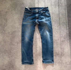 Levi's 514 blå jeans straight fit - Säljer ett par klassiska Levi's 514 jeans i blå tvätt med snygga slitningar och raka ben. Midjan är mer som en 32-33.