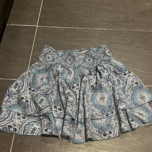 Fin kjol - Supersöt kortkjol i blått. Kjolen har volangdetaljer och resår i midjan för en bekväm passform. Kan även användas som en fin topp🩷