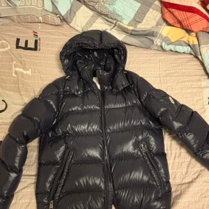 Mörkblå Moncler Maya pufferjacka - Lite intressekoll på min Maya. Den är i flawless skick. Endast små spår av användning men i princip perfekt. Storlek 2 som är s/m. Kan hitta tags och ”triangeln” som ingick. Självklart äkta, köptes för några år sen från garmsmarket. Skriv vid fler frågor eller bilder.