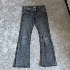 Grå bootcut jeans från Gina Tricot - Snygga grå jeans från Gina Tricot i storlek 146. Modellen har klassisk femficksdesign, låg midja och bootcut-ben. Jeansen är tillverkade i ett mjukt bomullsmaterial med en lätt tvättad look och markerade sömmar.