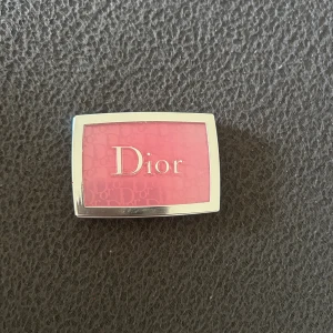 Dior rosa rouge i kompakt - Snyggt rosa rouge från Dior i en stilren kompakt dosa med silverram och genomskinligt lock. Perfekt för att ge kinderna en fräsch och poppig färg. Lätt att ta med i väskan och enkel att applicera med borste.