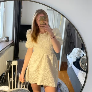 Krämvit kort klänning med puffärm - Supersöt kort klänning med puffärmar och rosett bak. Perfekt till studenten. Aldrig använd med prislappar kvar