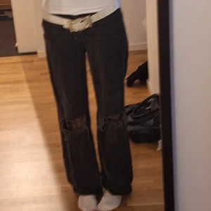 Svarta bootcut jeans med hål - Säljer ett par svarta bootcut jeans med slitna hål på knäna. 