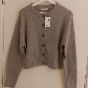 Kofta från Lager 157 (ny med prislapp) - Mjuk beige kofta från Lager 157 i storlek S. Den är helt ny med prislapp kvar. Koftan har knappar framtill och slitsar på sidorna. Perfekt för en chill höst kofta eller bara en mys tröja. Den sicks absolut inte utan är hur mjuk som helst.