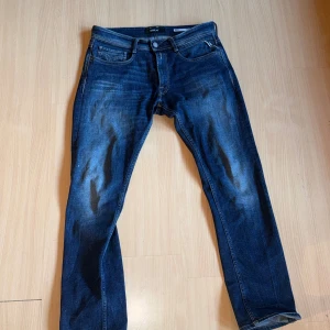 Blå Replay jeans Rocco - Säljer ett par snygga blå jeans från Replay, modell Rocco. Jeansen har klassisk femficksdesign, raka ben och tydliga slitningar framtill för en cool look. Materialet är jeans i bomull och passformen är normal. Perfekta för dig som gillar stilrena och bekväma jeans.