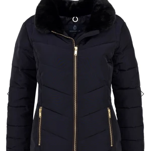 Svart pufferjacka från Stockh LM, stl 36 - Snygg svart pufferjacka från Stockh LM med guldiga dragkedjor och mjuk fuskpäls vid kragen. Jackan har quiltad design, långa ärmar och emblem på ärmen. Perfekt för kalla dagar och riktigt stilren look.