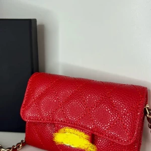 Röd quiltad axelväska  - Supersnygg röd axelväska från  i quiltat skinn med kedjerem i guld och rött läder. Klassisk design med lock och elegant struktur på ytan. Perfekt för dig som vill sticka ut med en ikonisk och lyxig accessoar.