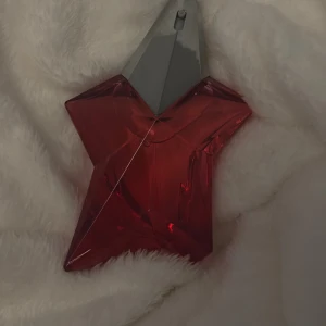 Mugler - Angel Nova - Unik parfym i röd stjärnformad flaska från Mugler. Perfekt för dig som vill sticka ut med din stil och gillar cool design. Flaskan är både snygg och annorlunda – ett måste för samlingen!                                                  Som ny, endast testsprutat. Doftfamilj: Fruktig  Toppnot: Hallon, Litchi  Hjärtnot: Damascena ros  Basnot: Akigalaträ, bezoin