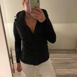 Svart dunväst med huva från Zara - Svart dunväst från Zara med huva. Västen är figursydd och sitter superfint. Perfekt för lager-på-lager och nu till hösten!