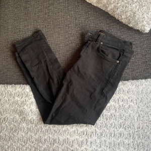 Svarta jeans från Nudie Jeans, 32/30 - Svarta jeans från Nudie Jeans med klassisk femficksdesign och diskreta svarta sömmar på bakfickorna. Jeansen har en rak passform och är tillverkade i mjukt jeanstyg. Perfekta för dig som gillar stilrena och enkla byxor. Hör av er vid frågor och inga defekter⚡️👌
