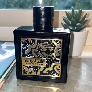 Qaed Al Fursan parfymflaska - Snygg parfym med unik design och guldiga detaljer. Perfekt för dig som vill sticka ut och visa din stil. Märket och flaskan ger en lyxig känsla. Volym och ingredienser syns ej på bilden. CA 90% kvar
